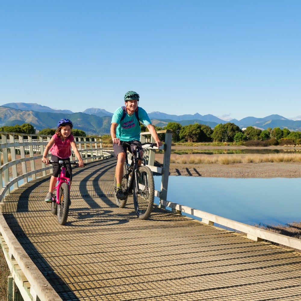 Cycling along a boardwalk on Waimea Estuary | Biking Tours with Children